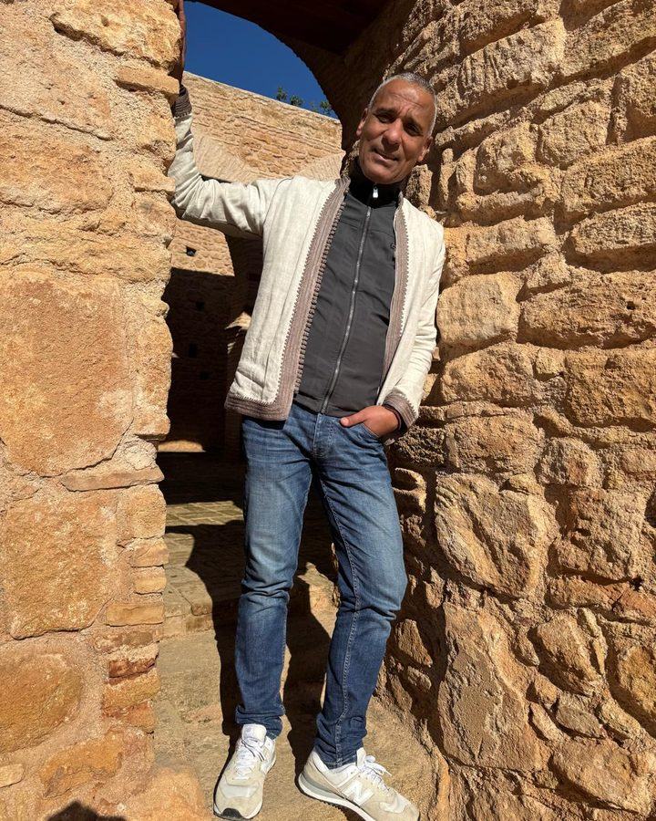 Adil dans une ruelle de pierre, adossé au mur d’un ksar