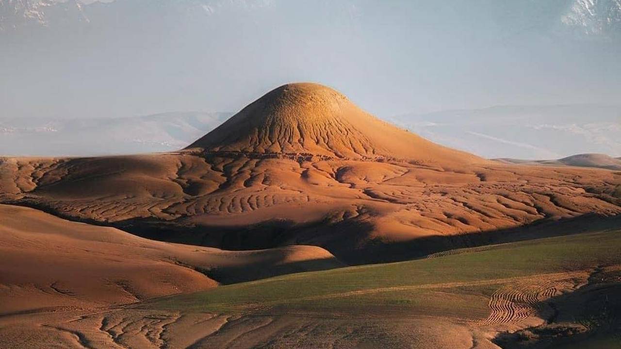 Une caravane solitaire traversant le désert d’Agafay, l’Atlas enneigé en fond