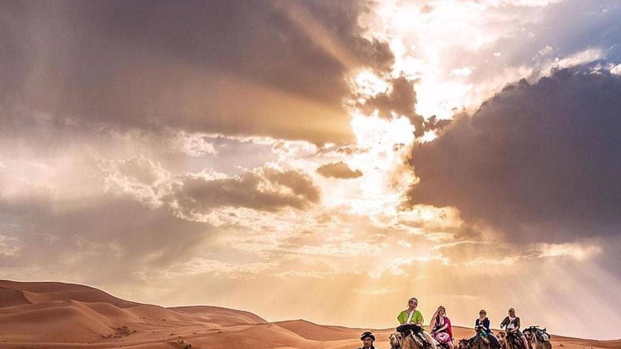 Une caravane traversant les dunes de l’erg Chebbi au coucher du soleil
