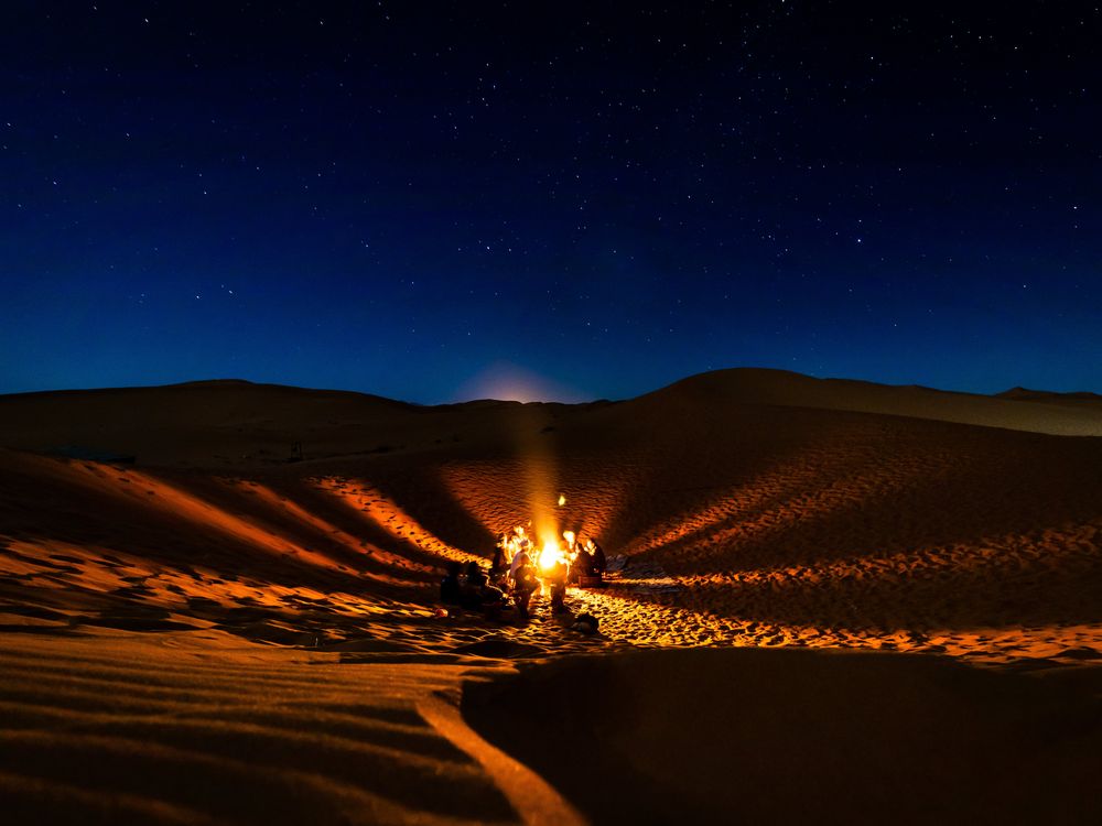 Un feu de bivouac sous les étoiles, au creux des dunes de l’erg Chebbi