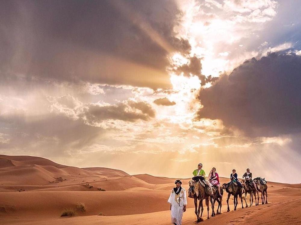 Une caravane traversant les dunes de l’erg Chebbi au coucher du soleil