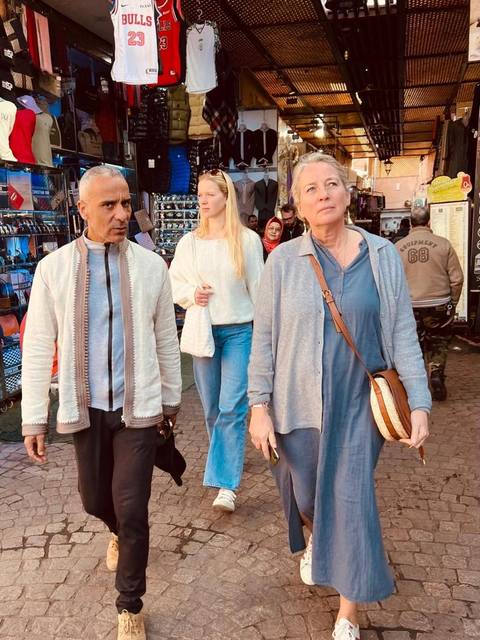 Adil marchant avec des visiteurs dans un souk couvert