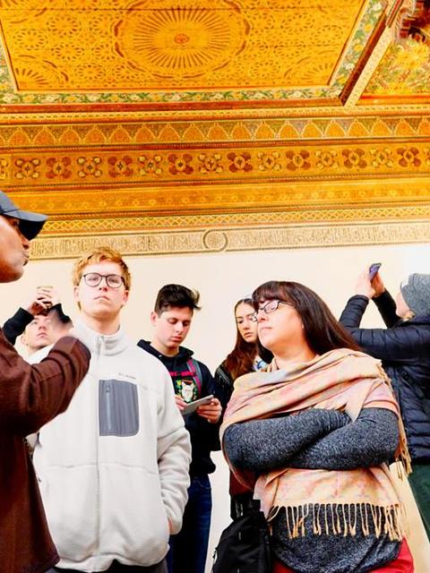Adil s’adressant à un groupe scolaire sous un plafond peint