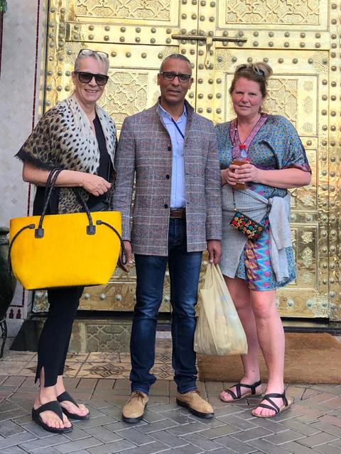 Adil avec deux visiteuses devant la porte en laiton d’un riad