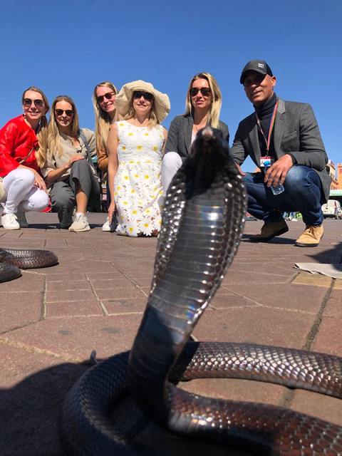 Adil et des visiteuses auprès des charmeurs de serpents à Jemaa el-Fna