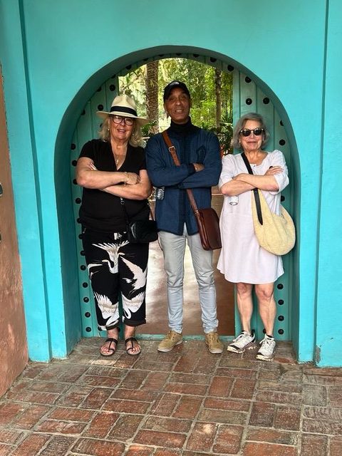 Adil and two guests in a turquoise garden doorway