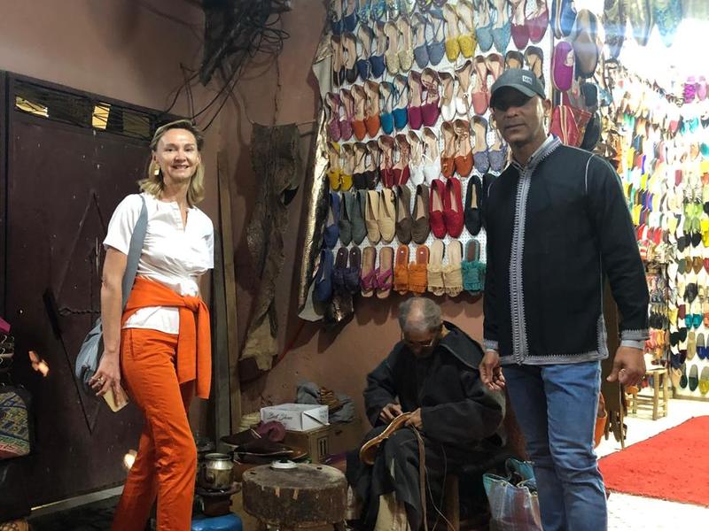 Adil et une visiteuse devant un étal de babouches dans les souks